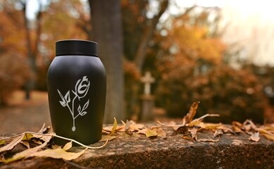 Fototapeta premium Black urn prepared for funeral in the cemetery in autumn. 