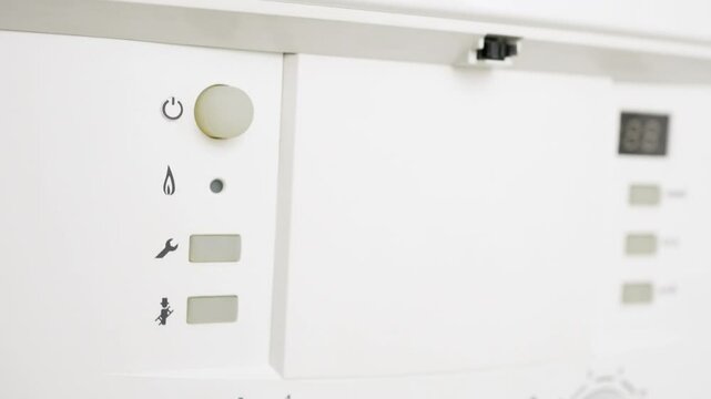 Cropped view of a man's hand pushing a button stop the boiler of heating and hot water