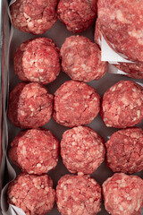 Semi finished patties and meatballs in a metal tray