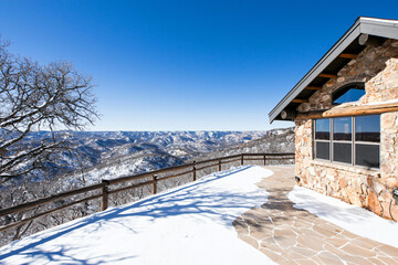 a winter hideaway featuring natural stone construction, timber accents, and panoramic mountain views, snowy landscape