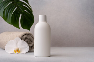 White bottle with orchid flower and rolled towel, symbolizing spa and skincare