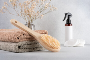 Bathroom essentials for self-care, featuring a bamboo body brush, soft towels, and organic skincare items