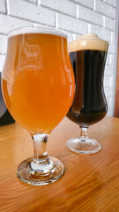 Glasses with light and dark beer on a dark background. Nuts and crackers