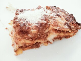 Close up of a piece of lasagna on a white plate.