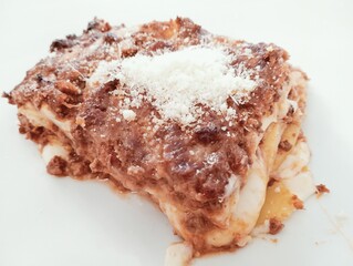 Close up of a piece of lasagna on a white plate.