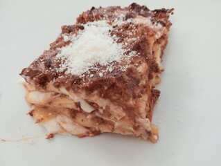 Close up of a piece of lasagna on a white plate.