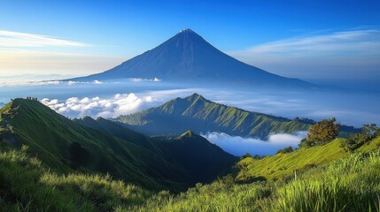 Naklejka premium Majestic view of a volcano surrounded by lush green hills and clouds at sunrise.