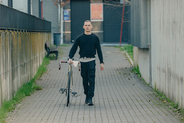 young man with bicycle walking on the street