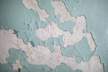 Cracked, peeling paint on the wall. A wall with old cracked blue paint. Patterns of cracks.