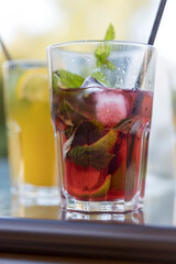 A glass of red drink with ice cubes and a lime slice