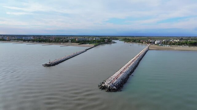 aerial view of a small fishing boat coming into the breakwater inlet Livenza, in Caorle, Italy