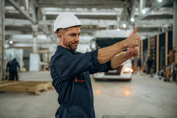 Hands gestures, helps to park the vehicle. Male worker is in the modern warehouse or manufacturing company