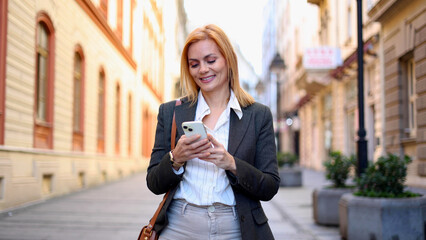 Beautiful woman walking through the city, using smartphone and enjoying