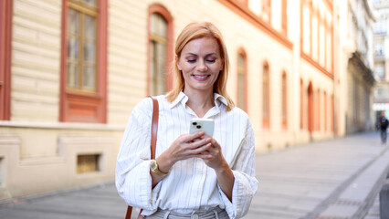 Beautiful woman walking through the city, using smartphone and enjoying