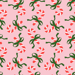 Seamless pattern with Christmas candy canes and bows on pink background. Cute background design for fabric, wrapping paper, textile, wallpaper