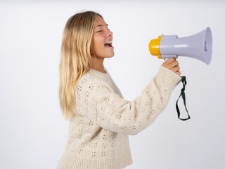 Funny caucasian teen girl wearing knitted sweater over white People sincere emotions lifestyle concept. Mock up copy space. Screaming in megaphone.