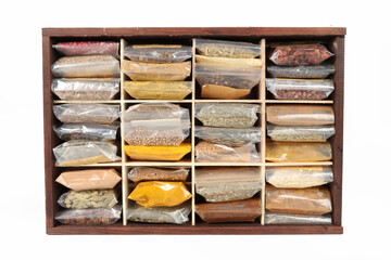 Multiple spice packets in a wooden box on a white background