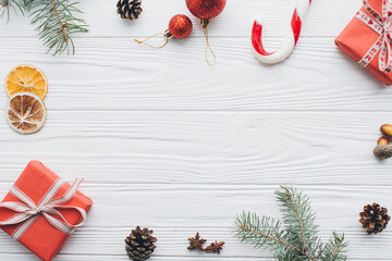 Christmas composition. Gifts, pine cones, fir branches, candy, spices and other decorations on wooden white background. Flat lay, top view.