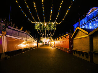 Empty Christmas market stalls illuminated with festive lights along Place Broglie in Strasbourg at night, after market closure