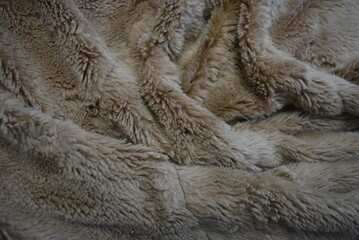 Fabrics, soft materials, bedspread, blanket made of synthetic materials. Gray-brown, fluffy and soft background in the form of long fur.