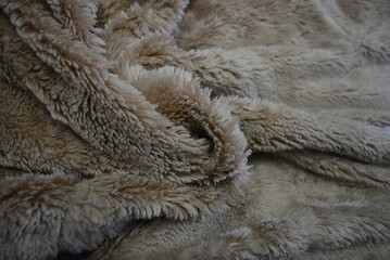 Fabrics, soft materials, bedspread, blanket made of synthetic materials. Gray-brown, fluffy and soft background in the form of long fur.