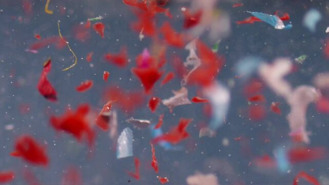 Microplastic particles swirl in water in slow motion, showcasing pollution in a lab sample and highlighting environmental waste issues.