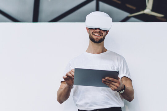 Positive man using tablet in virtual reality headset - Powered by Adobe