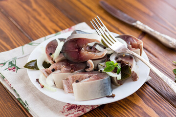 lightly salted mackerel with onions and spices on a wooden table