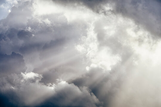 Light rays shining through white cumulus clouds