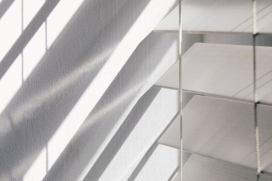 Close-up of white window blinds and shadows