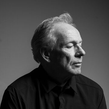 Studio portrait of serious senior man in black shirt, black and white