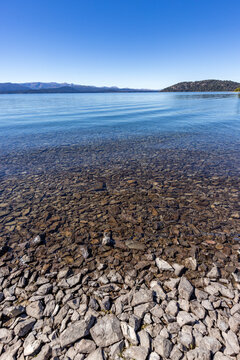 Rocky beach and calm lake on sunny day