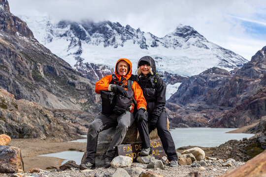Argentina, Santa Cruz, El Chalten, Portrait of smiling hikers sitting at trails end below Marconi Glacier