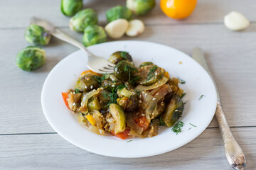 Brussel sprouts cooked with vegetables and spices, on a wooden table