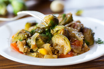 Brussel sprouts cooked with vegetables and spices, on a wooden table