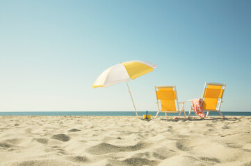 USA, Massachusetts, Nantucket, Two yellow beach chairs and umbrella on sandy beach facing ocean