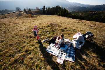 Fototapeta premium Family enjoying a picnic on a sunny hillside meadow