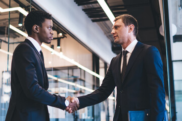 Multiethnic independent startuppers shaking hands at office