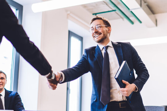 Business partners shaking hands over table
