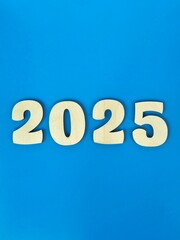 Large wooden numbers representing the year 2025 displayed on a vibrant blue background