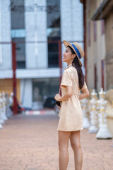 Obraz premium A woman wearing a hat and a dress is walking down a street