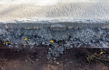 Obraz premium A cracked sidewalk with a pile of gravel and leaves on it