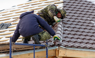 A man in a green and black uniform is working on a roof