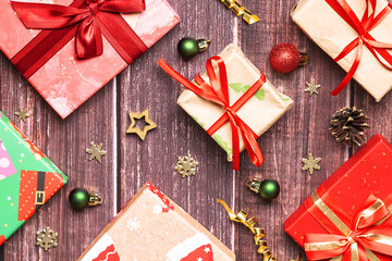 Festive Christmas and New Year composition with bright gift boxes and shining decorations on dark wooden background top view.
