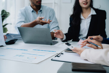 Strategic Business Meeting: A diverse team collaborates around a table, reviewing documents and engaging in lively discussion.