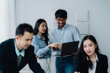 Collaborative Success: A diverse team of young Asian business professionals collaborates on a project, showcasing teamwork and innovation in a modern office setting.  