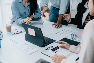 Strategic Collaboration: Diverse team brainstorming around a table, reviewing documents and using digital tablet.  Captures the essence of modern business collaboration. 