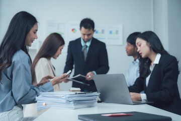 Focused Business Team Meeting: A diverse group of professionals collaborates intensely around a table, laptops and documents spread before them.