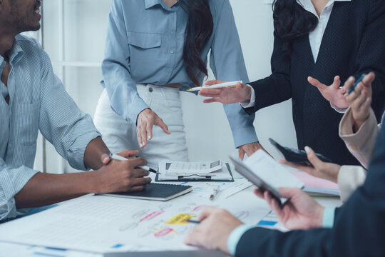Collaborative Brainstorming: A diverse team of professionals huddle around a table, engaged in a lively discussion, their hands gesturing and their expressions focused.