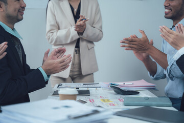 Business Team Applauding Success: A diverse group of professionals applauds enthusiastically in a...